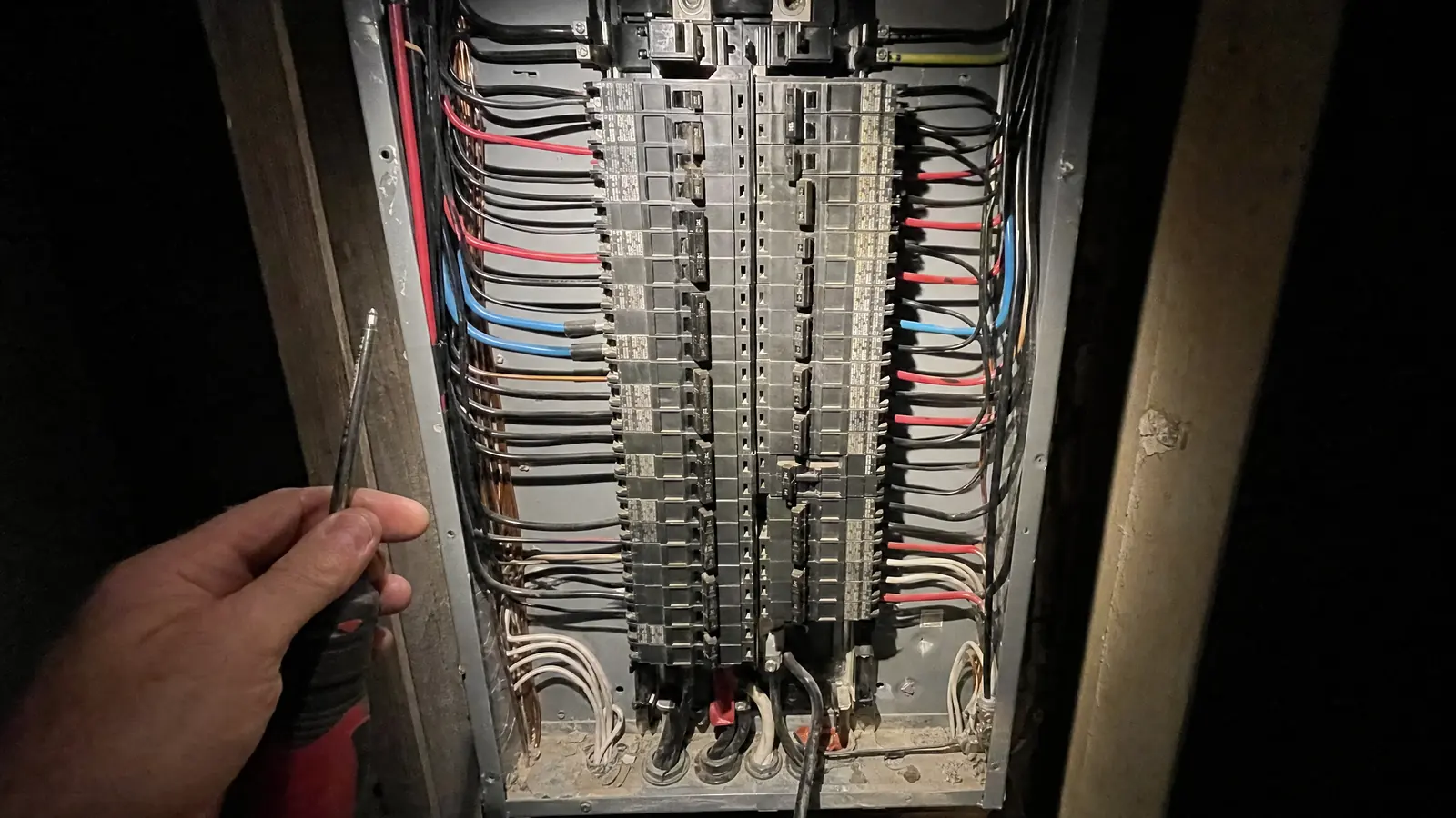 An open electrical distribution panel with its cover removed, showing two columns of breakers and colour-coded conductors dressed neatly down each side.