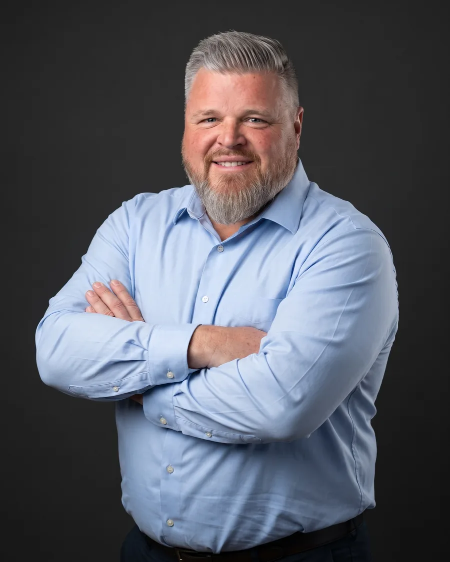 Aaron Gaddy, founder of Bydand CMI, arms folded, against a dark grey background.